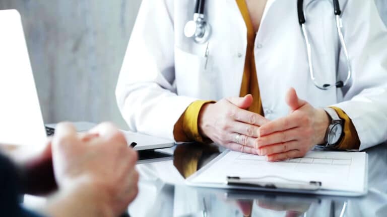 Doctor and patient consultation with clipboard and medication notes